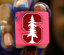Block with Stanford S insignia held by a hand covered in paint