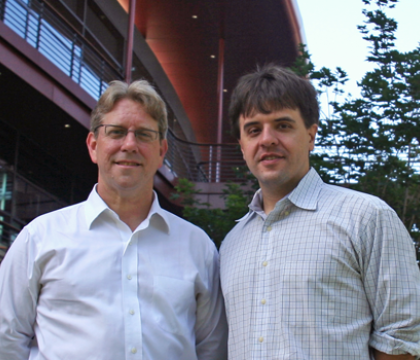 Outdoor photo of two male faculty members standing together and smiling.